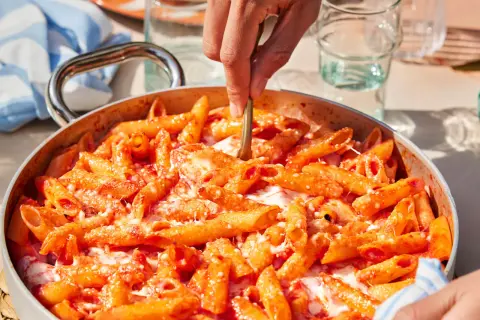 Un primo piatto invitante: pasta alla sorrentina fumante, con pomodoro e mozzarella filante, pronta per essere servita.