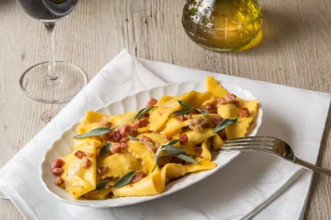 Piatto di casoncelli alla bergamasca conditi con burro, salvia e pancetta croccante.