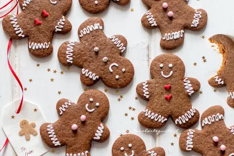 Biscotti di pan di zenzero decorati con glassa bianca e cuoricini rossi, pronti per essere gustati.