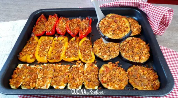 Delizioso piatto di verdure gratinate al forno: peperoni rossi e gialli ripieni, zucchine a rondelle e melanzane a fette, tutti dorati e croccanti.