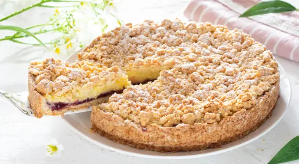 Deliziosa sbriciolata alla crema con un ripieno di marmellata di frutti di bosco, cosparsa di zucchero a velo.