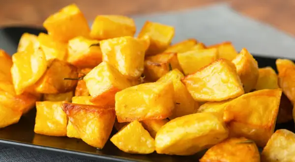 Patate al forno veloci, dorate e croccanti, servite su un piatto nero. Perfette per un contorno rapido e gustoso.
