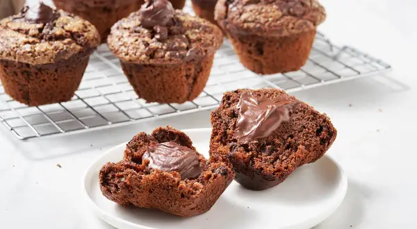 Muffin al cioccolato soffici e golosi, uno aperto rivela un cuore cremoso. Perfetti per una pausa dolce.