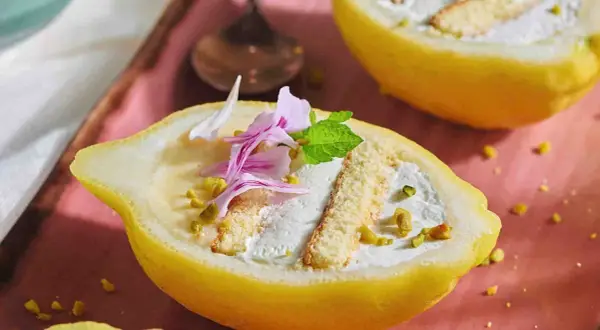 Delizia al limone: un dolce fresco e invitante, servito in un limone scavato, con crema, pan di spagna e pistacchi.