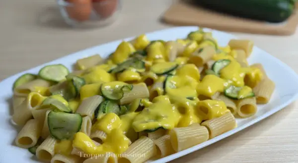 Piatto di rigatoni conditi con una cremosa salsa gialla e zucchine a rondelle. Una deliziosa carbonara di zucchine pronta da gustare.