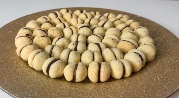 Un vassoio dorato pieno di deliziosi baci di dama, biscotti friabili con un cuore di cioccolato.