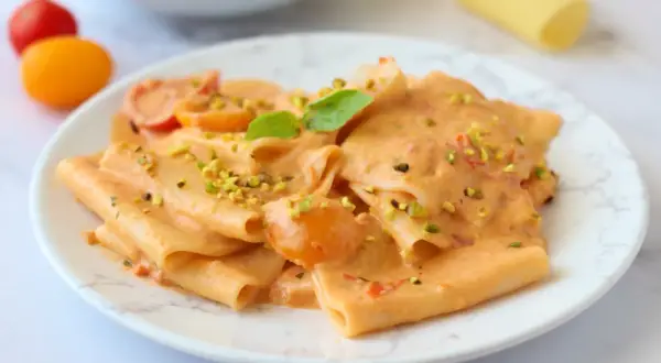 Paccheri cremosi con pomodorini e pistacchi, un piatto di pasta con stracciatella che invita a un morso goloso.