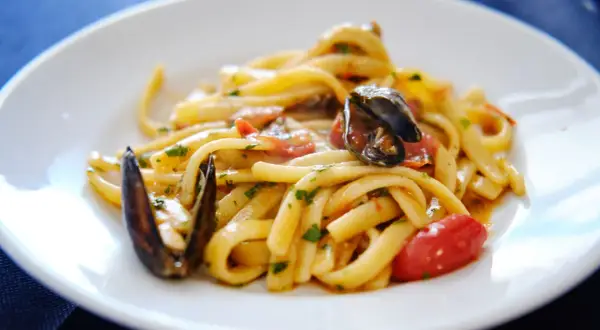 Un piatto invitante di scialatielli ai frutti di mare, con cozze, pomodorini e prezzemolo fresco.