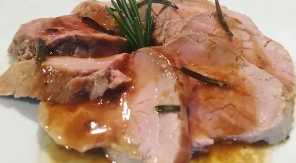 Fette succulente di filetto di maiale al forno, bagnate in un sughetto saporito e guarnite con rosmarino fresco.