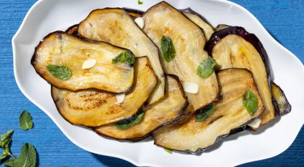 Fette di melanzane grigliate, condite con aglio e menta fresca, un contorno di verdure saporito e colorato.
