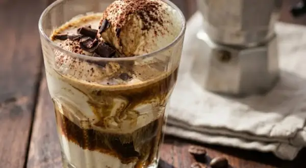 Un delizioso affogato al caffè, con gelato alla vaniglia, cacao e scaglie di cioccolato, pronto per essere gustato.