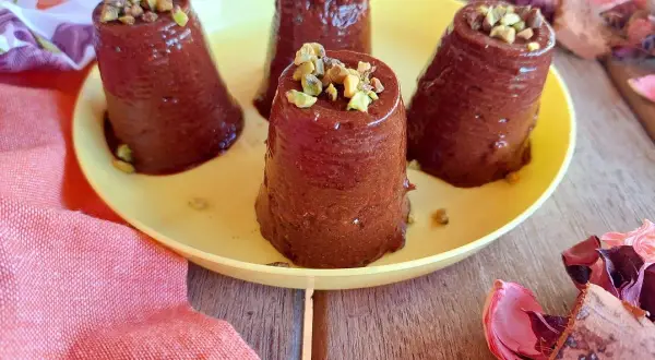 Deliziosi budini cachi e cacao, guarniti con pistacchi tritati, su un piatto giallo.
