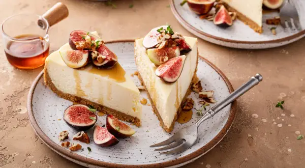 Delizioso cheesecake ai fichi, guarnito con fichi freschi, noci e miele dorato.
