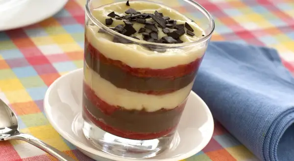 Delizioso bicchiere di zuppa inglese tradizionale, con strati di crema pasticcera, cioccolato e pan di Spagna, guarnito con scaglie di cioccolato.