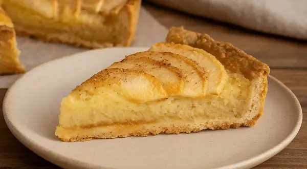 Una fetta di crostata di mele, con la sua base dorata, ripieno cremoso e mele affettate in superficie, pronta per essere gustata.