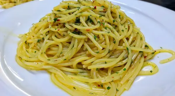 Spaghetti conditi con aglio, olio e peperoncino, guarniti con prezzemolo fresco. Un classico piatto italiano pronto da gustare.