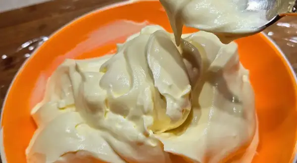 Una ciotola arancione piena di soffice crema al mascarpone, pronta per essere gustata.