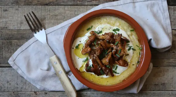 Polenta cremosa con funghi finferli saltati, un piatto rustico e saporito.