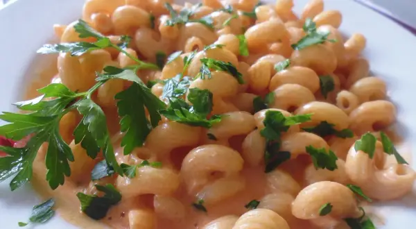 Un piatto invitante di pasta al limone cremosa, guarnita con prezzemolo fresco.