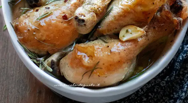 Cosce di pollo succulente, dorate e profumate al rosmarino e aglio, servite in una ciotola bianca.