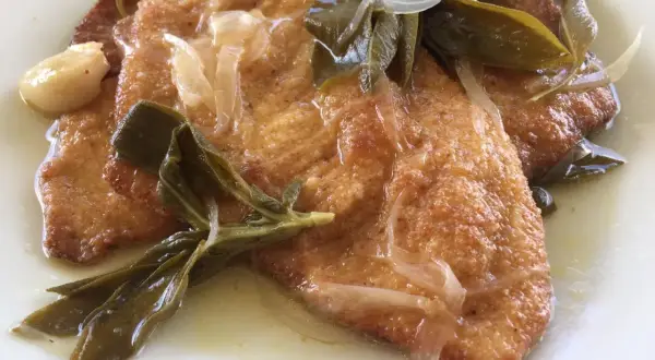 Bistecche in carpione dorate e succulente, condite con cipolle, salvia e aglio in una salsa profumata.