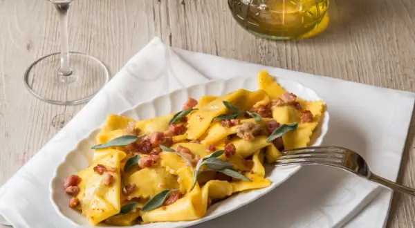 Piatto di casoncelli alla bergamasca conditi con burro, salvia e pancetta croccante.