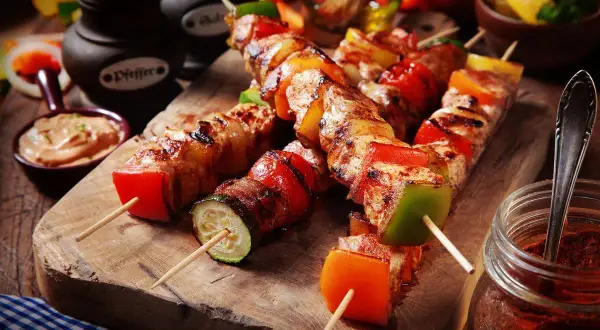 Spiedini di carne succulenti con peperoni, zucchine e pomodori, pronti per essere gustati.