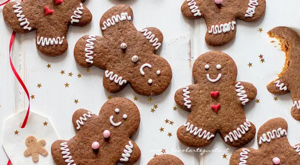 Biscotti di pan di zenzero decorati con glassa bianca e cuoricini rossi, pronti per essere gustati.