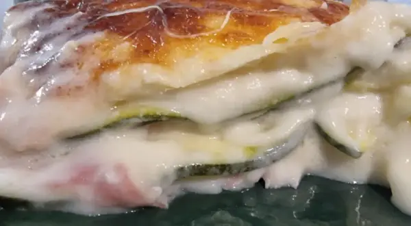 Porzione di lasagne di zucchine cremose e dorate, con strati di verdura e besciamella filante.