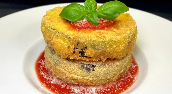 Due cordon bleu di melanzane impilati, dorati e croccanti, su un letto di salsa di pomodoro e basilico fresco.