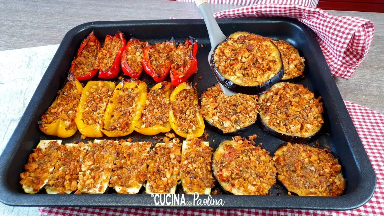 Delizioso piatto di verdure gratinate al forno: peperoni rossi e gialli ripieni, zucchine a rondelle e melanzane a fette, tutti dorati e croccanti.
