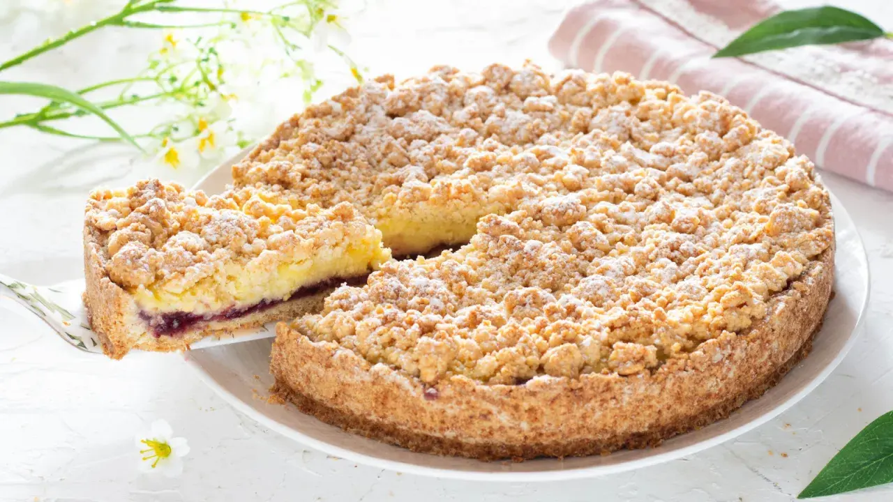 Deliziosa sbriciolata alla crema con un ripieno di marmellata di frutti di bosco, cosparsa di zucchero a velo.