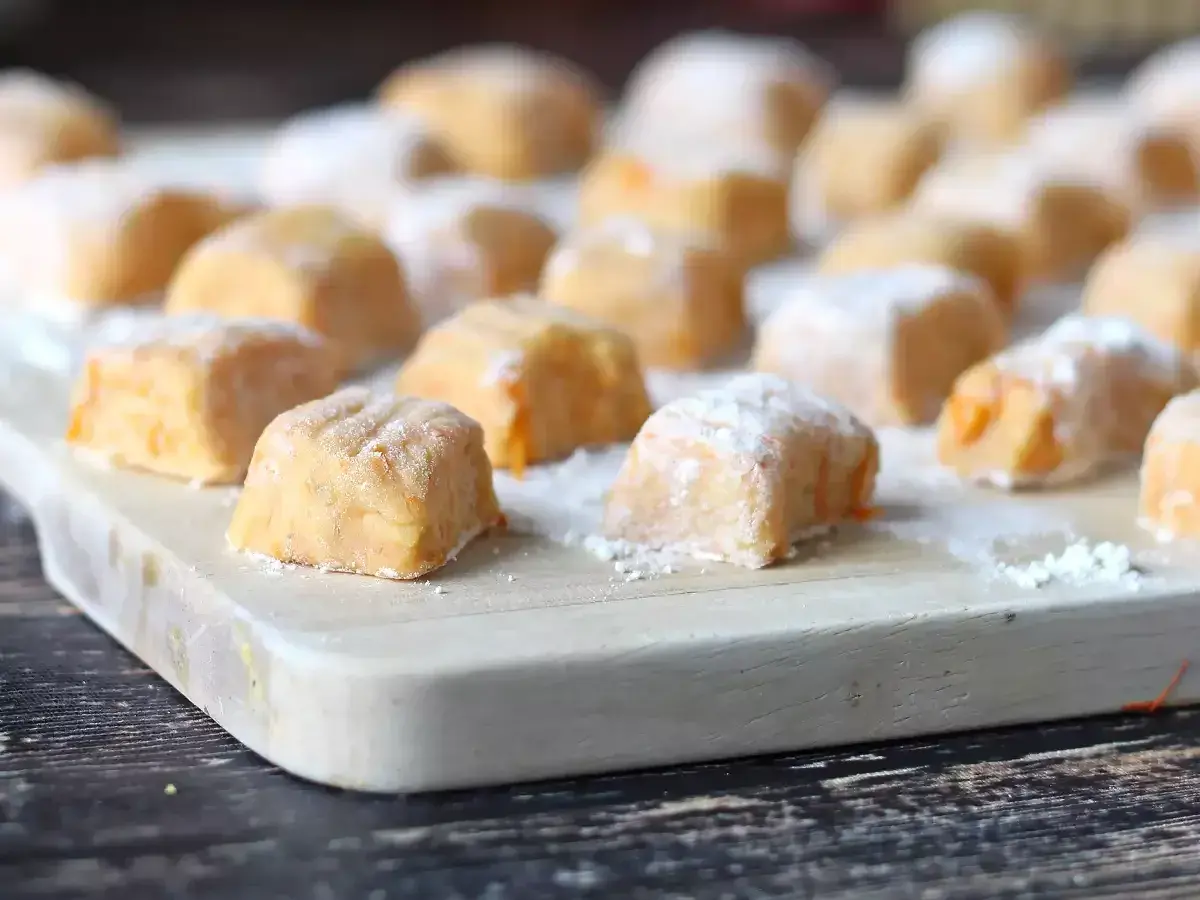 Gnocchi di zucca fatti in casa, morbidi e colorati, pronti per essere cucinati su un tagliere di legno.