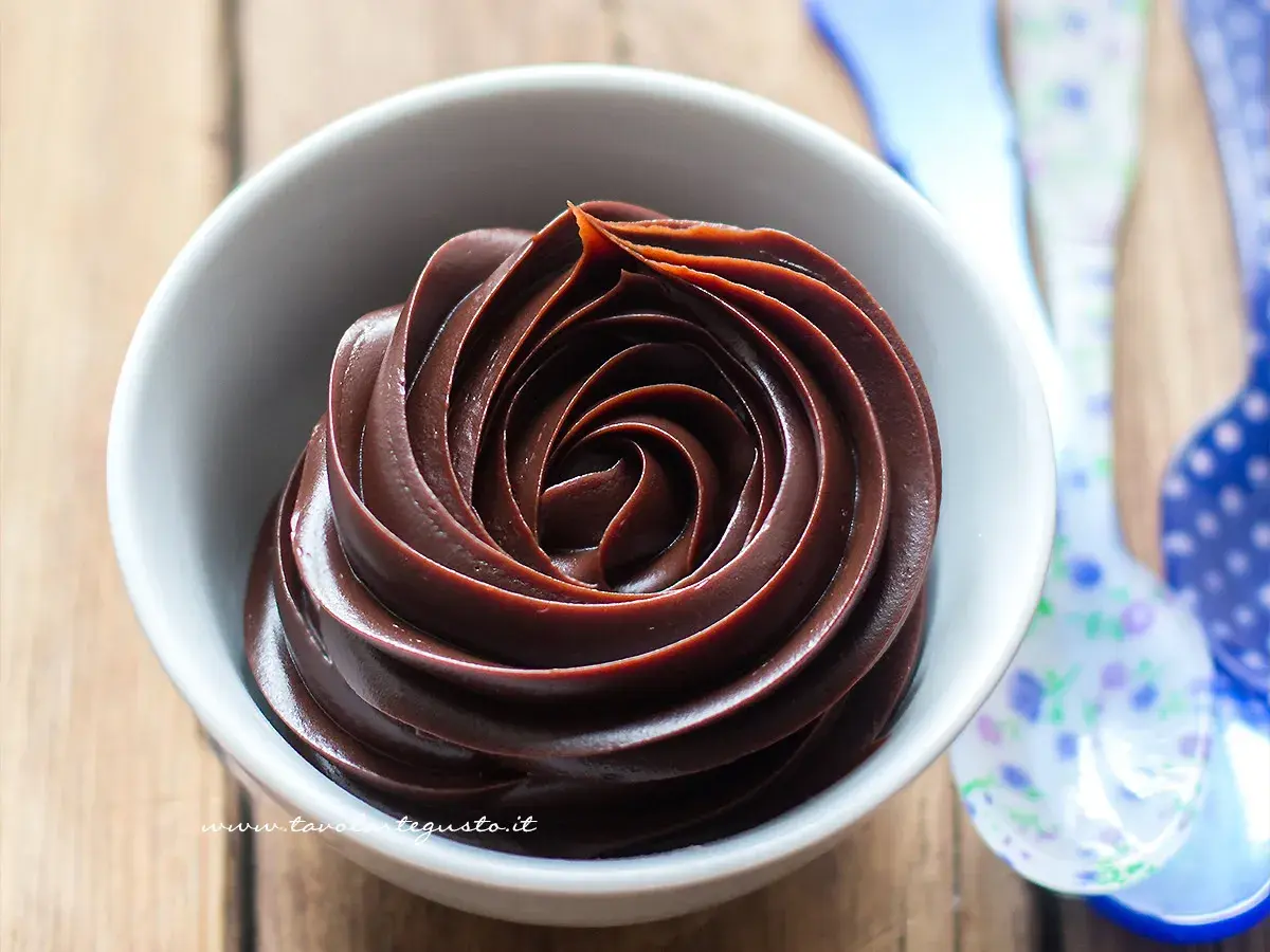 Una spirale perfetta di ganache al cioccolato, lucida e invitante, in una ciotola bianca.