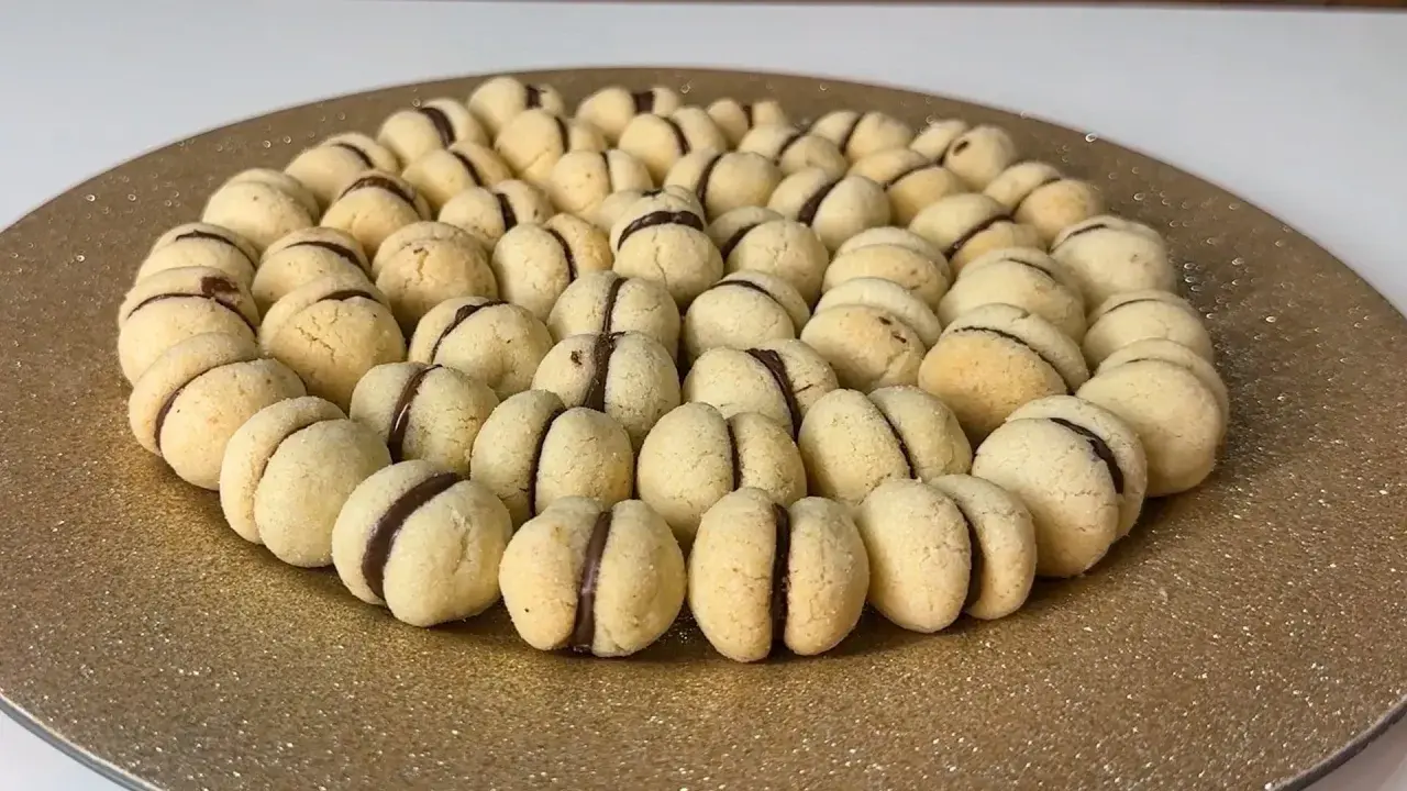 Un vassoio dorato pieno di deliziosi baci di dama, biscotti friabili con un cuore di cioccolato.