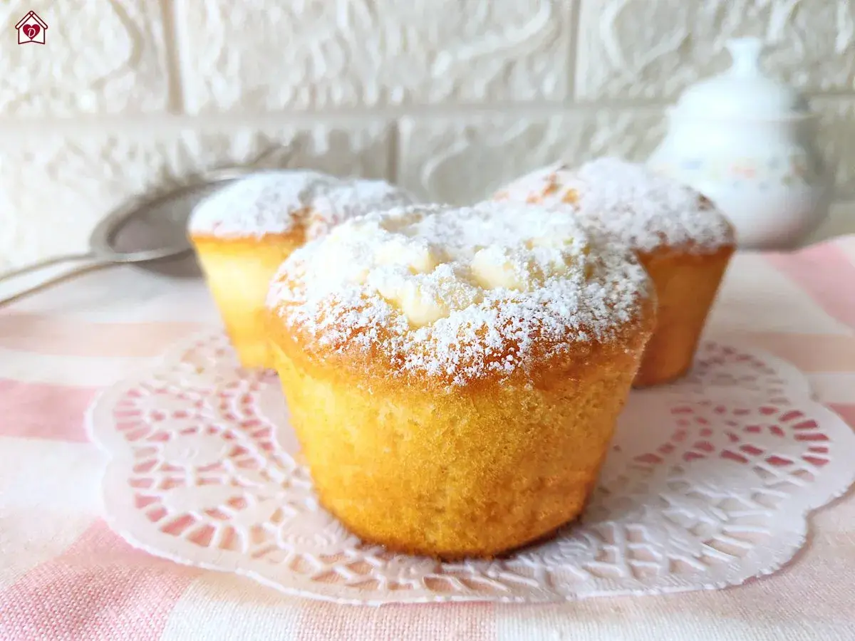 Muffin soffici e dorati, spolverati di zucchero a velo, perfetti per una ricetta facile e golosa.