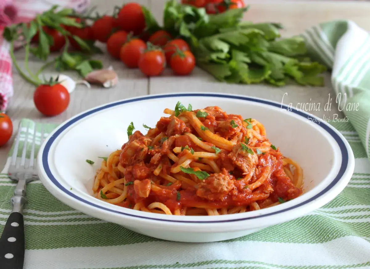 Un piatto di spaghetti al tonno, un classico della cucina di Vane, con pomodorini freschi e prezzemolo.