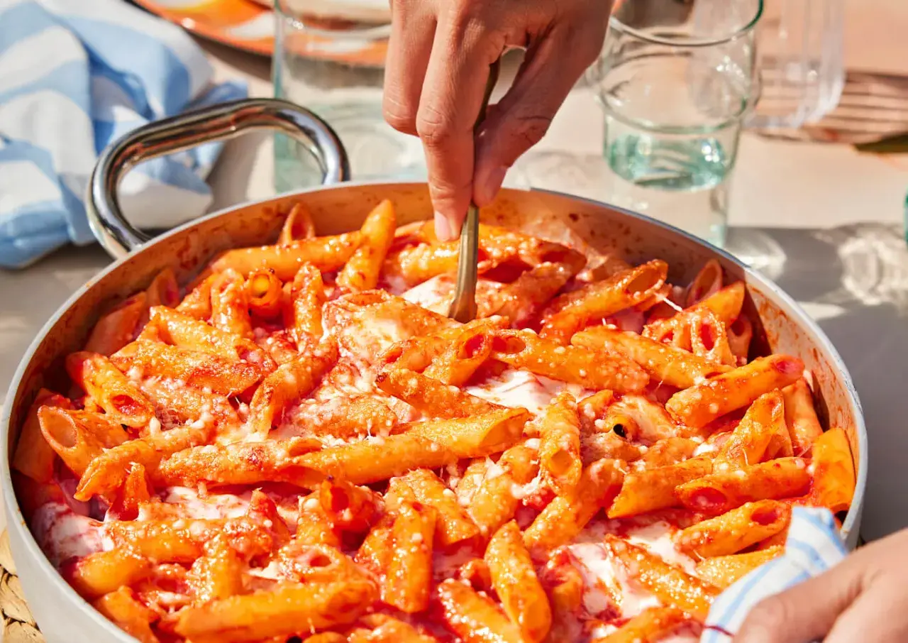 Un primo piatto invitante: pasta alla sorrentina fumante, con pomodoro e mozzarella filante, pronta per essere servita.