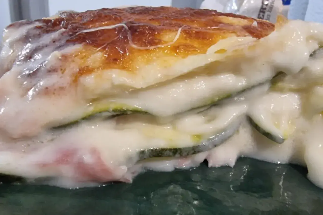 Porzione di lasagne di zucchine cremose e dorate, con strati di verdura e besciamella filante.