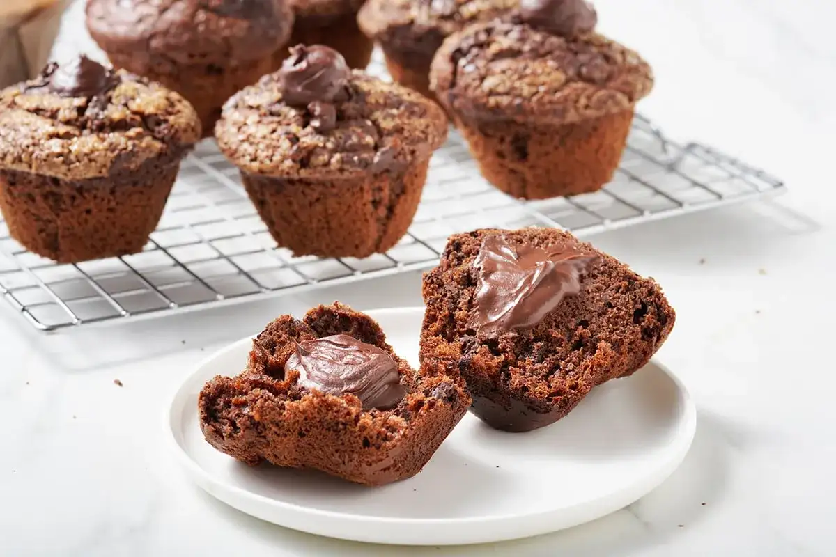Muffin al cioccolato soffici e golosi, uno aperto rivela un cuore cremoso. Perfetti per una pausa dolce.