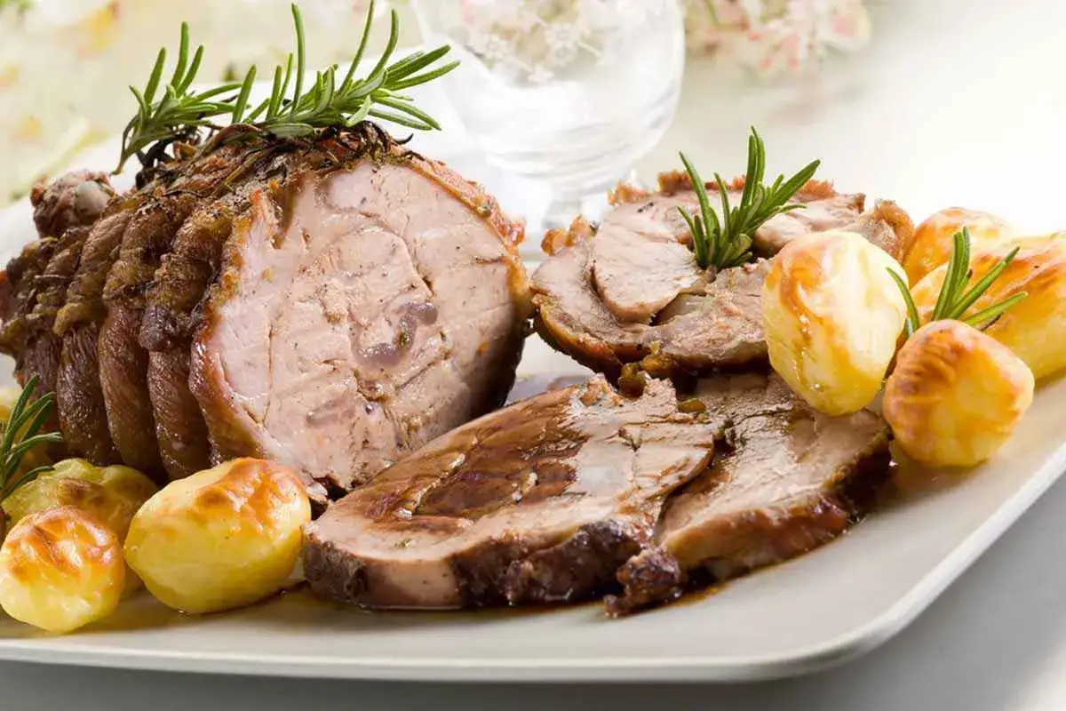 Magatello di vitello arrosto, affettato e servito con patate novelle dorate e rametti di rosmarino.