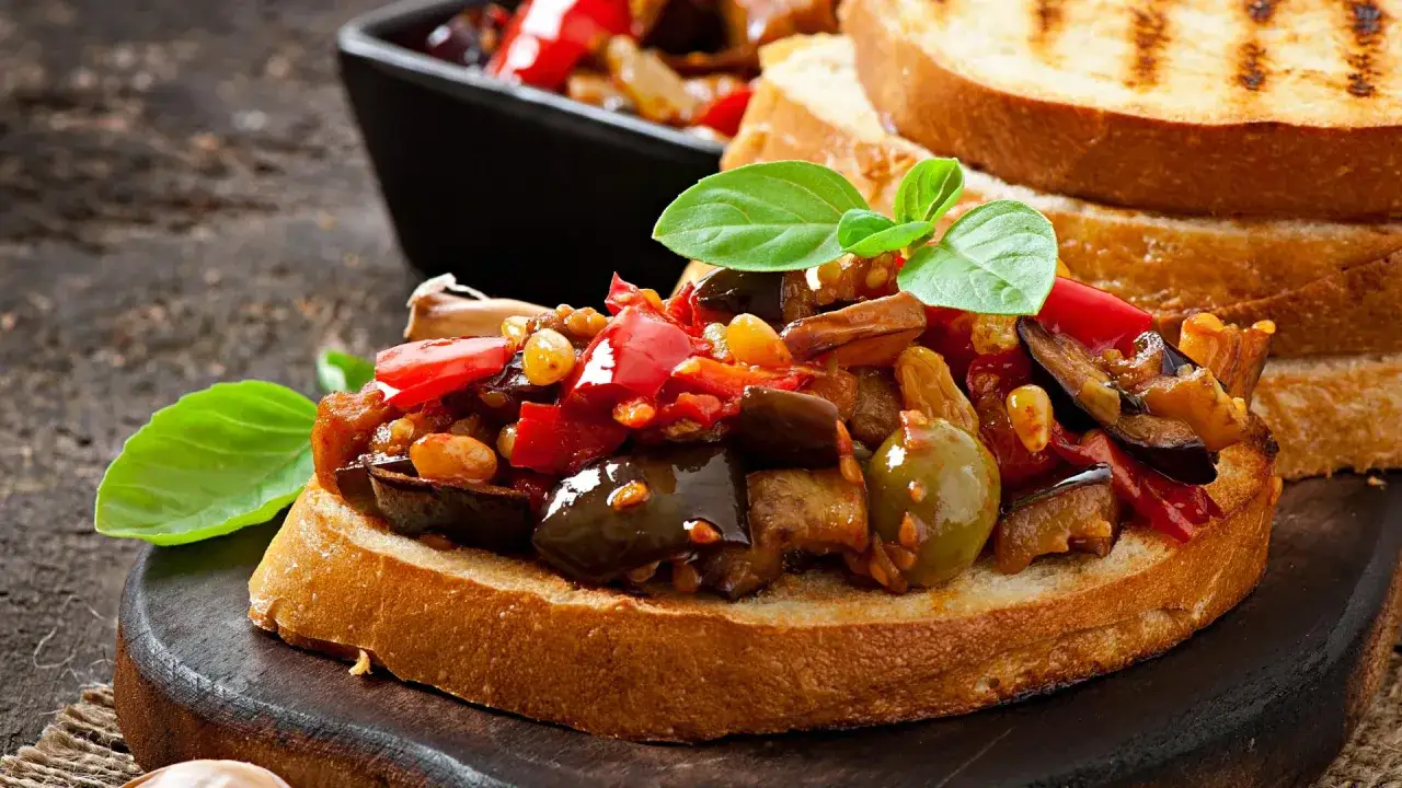 Bruschetta con peperonata e melanzane, un antipasto saporito che celebra i sapori mediterranei.