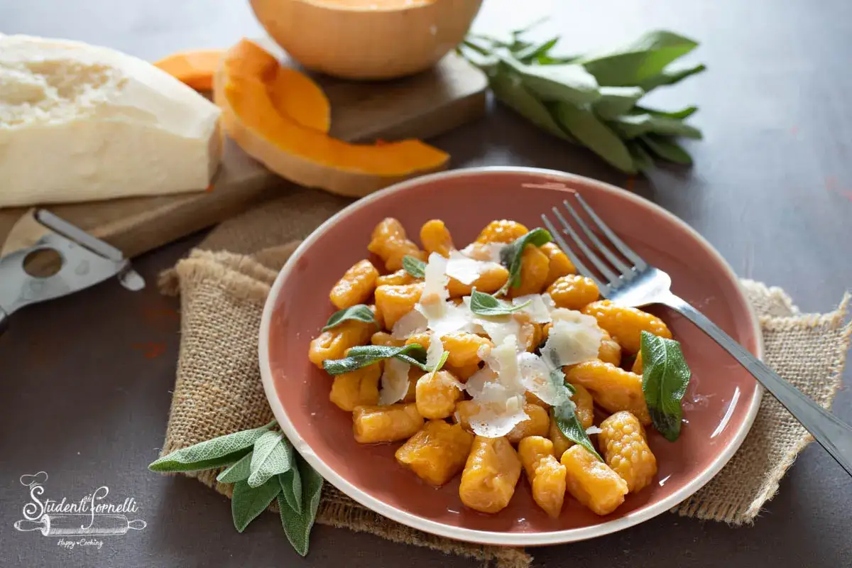 Piatto di gnocchi di zucca fatti in casa, conditi con salvia e parmigiano grattugiato. Ingredienti freschi e un tocco di felicit&agrave;.