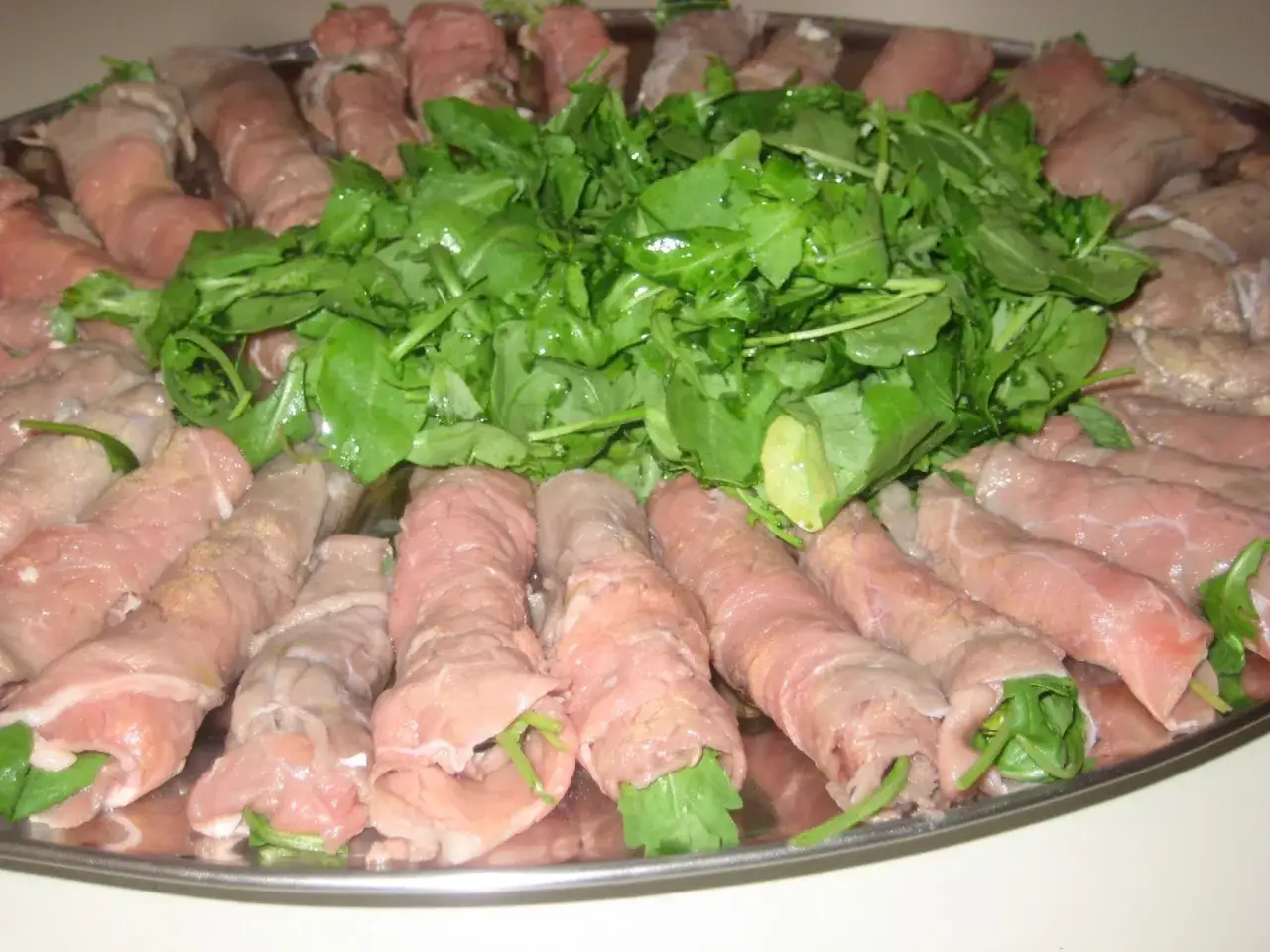 Rotolini di paillard di vitello con rucola fresca, pronti per essere cucinati.