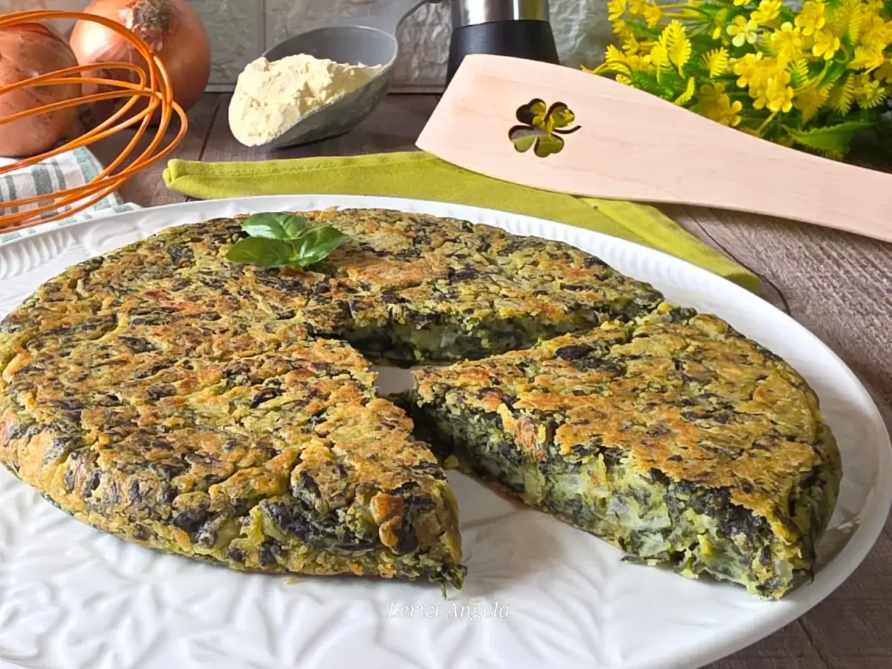 Frittata di spinaci dorata e gustosa, guarnita con basilico fresco. Sullo sfondo, ingredienti per prepararla.