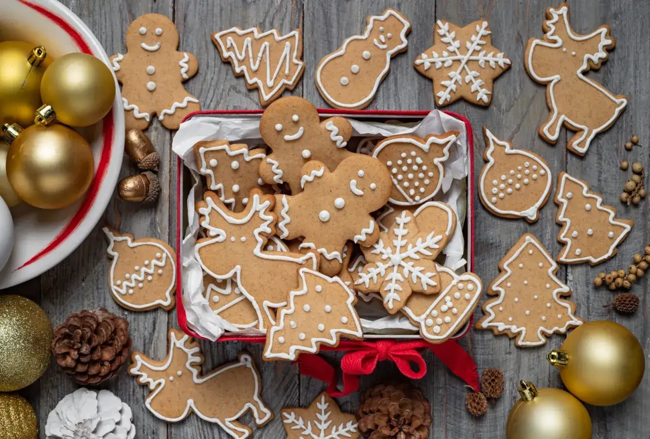 Un assortimento di biscotti di pan di zenzero a tema natalizio, tra cui omini, renne e alberi, decorati con glassa bianca.