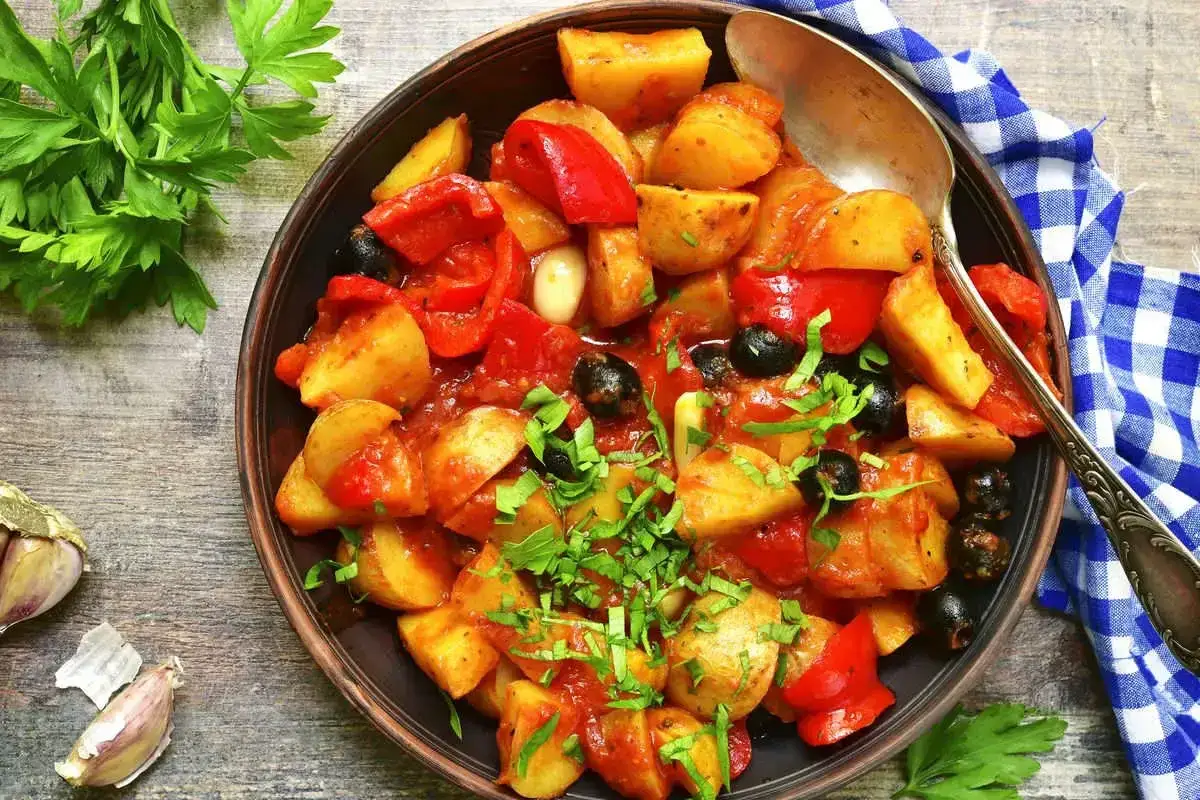 Piatto di patate e peperoni rossi, olive nere e aglio, un'idea per ricette con peperoni gustose e semplici.