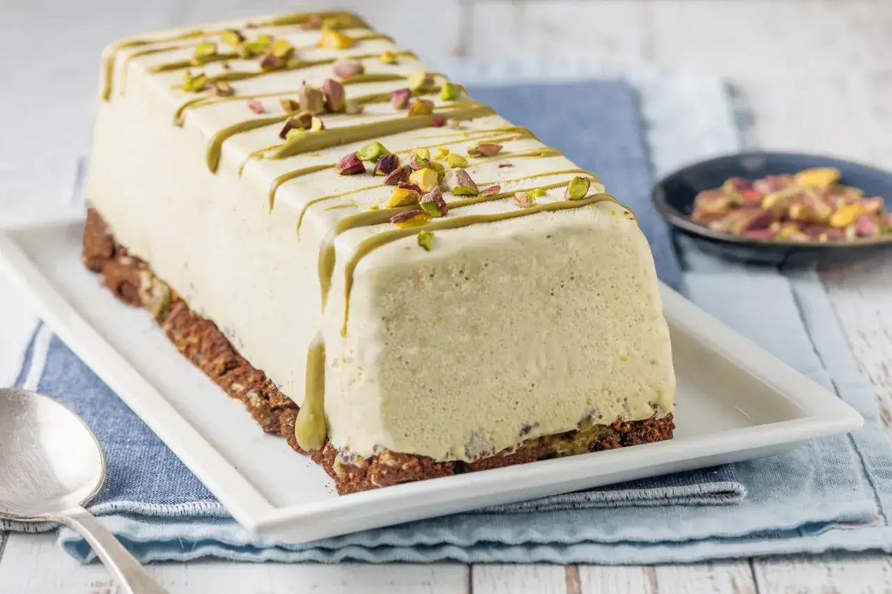 Delizioso semifreddo al pistacchio, con glassa verde e granella di pistacchi, su una base croccante.