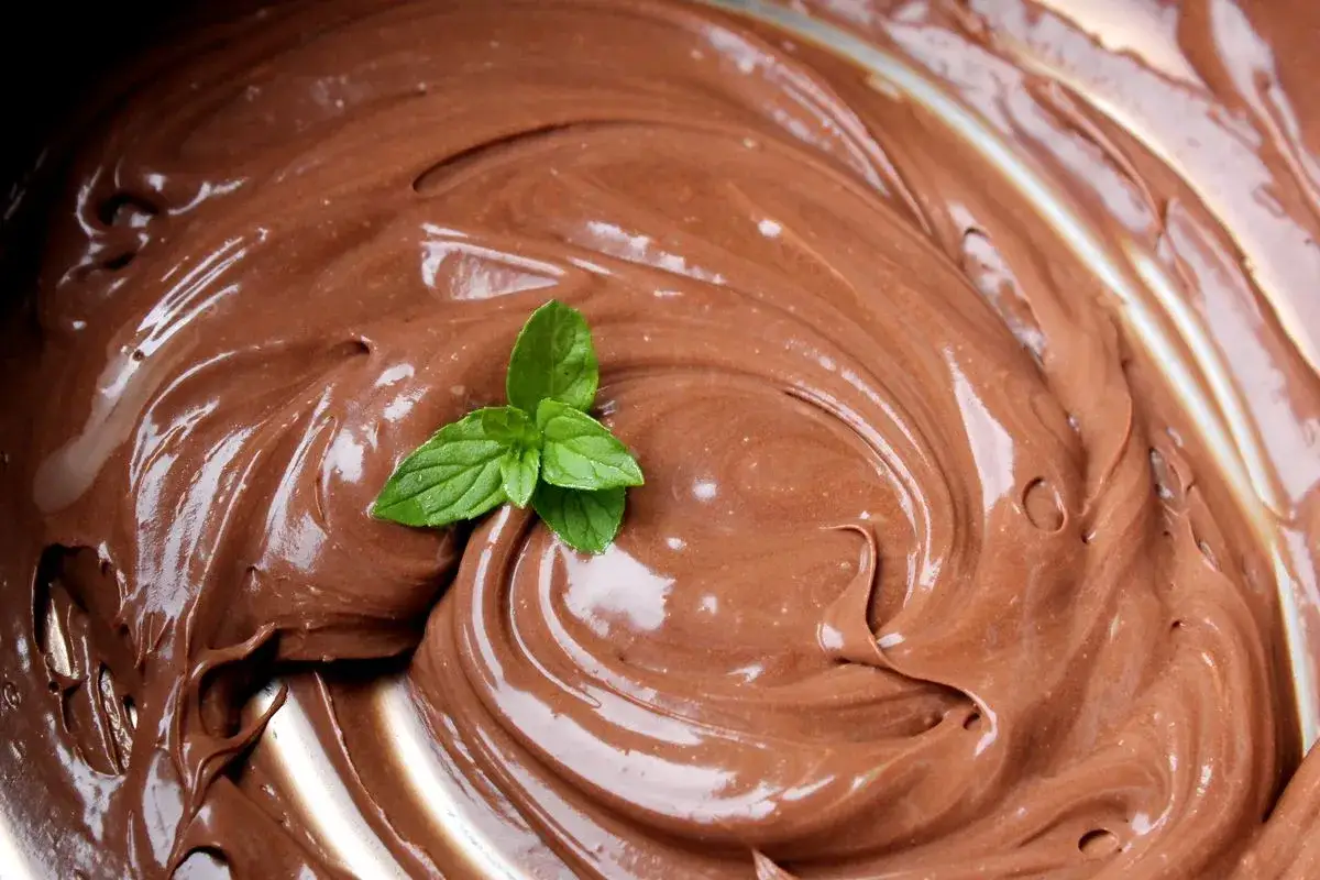 Una spirale di lucida ganache al cioccolato, con una fogliolina di menta fresca a decorare.