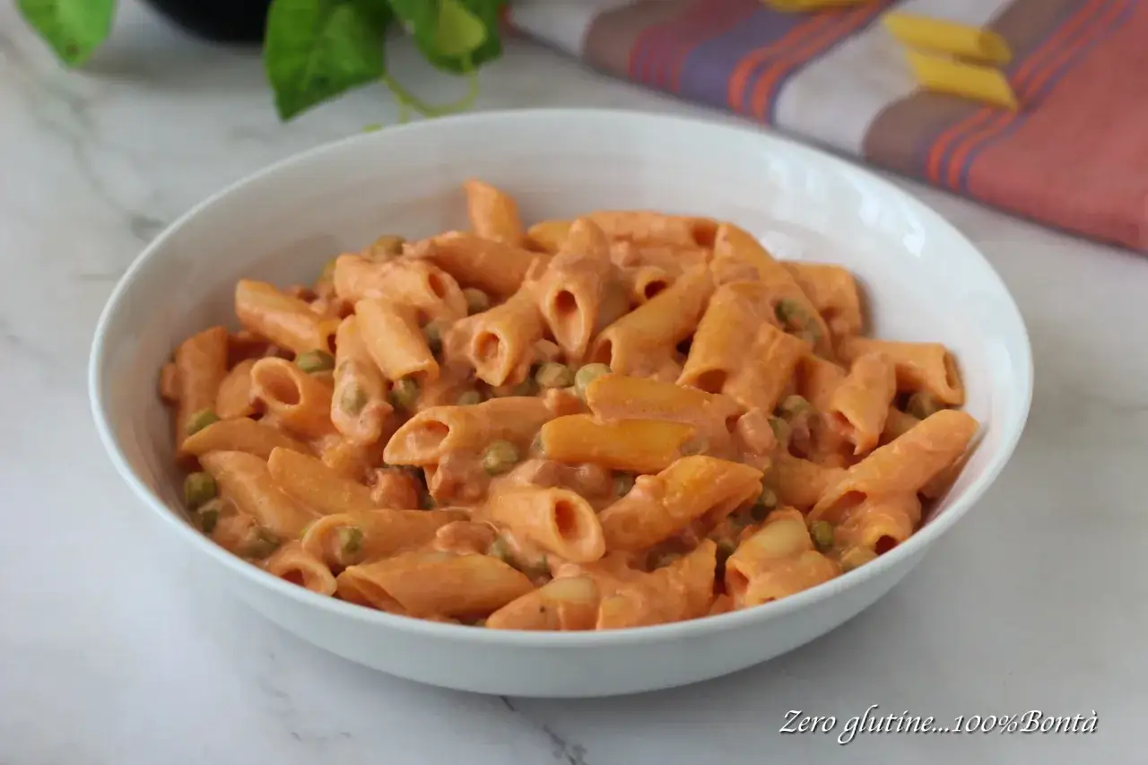 Penne ai 7 peccati, un piatto cremoso con piselli e una salsa rosa invitante, servito in una ciotola bianca.